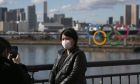 Μία τουρίστας φοράει μάσκα για προστασία από τον κορονοϊό μπροστά από τους ολυμπιακού κύκλους στην περιοχή Οντάιμπα του Τόκιο, Τετάρτη 29 Ιανουαρίου 2020
