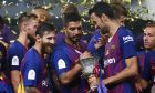 Barcelona's Lionel Messi, Luis Suarez and Sergio Busquets, from left to right, look at the trophy after winning the Spanish Super Cup soccer match between Sevilla and Barcelona in Tangier, Morocco, Sunday, Aug. 12, 2018. Barcelona won 2-1. (AP Photo/Mosa'ab Elshamy)