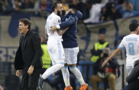Marseille's head coach Rudi Garcia, left, reacts on the field while his players celebrate their 5-2 win over RB Leipzig at the end of the Europa League quarter final second leg soccer match at the Velodrome stadium in Marseille, southern France, Thursday, April 12, 2018. Marseille defeated Leipzig 5-2. (AP Photo/Claude Paris)