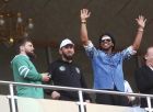 In this photo taken on Sunday, July 16, 2017, Brazilian soccer star and former FC Barcelona player Ronaldinho, right, greets fans as Chechen regional leader Ramzan Kadyrov, left, stands next to him at the stadium in Grozny, Russia. Ronaldinho had visited Grozny, Russia, to attend the relaunch of the city's football club. (AP Photo/Musa Sadulayev)