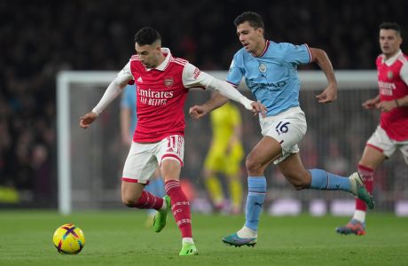 Arsenal's Gabriel Martinelli, left, challenges for the ball with Manchester City's Rodri during the English Premier League soccer match between Arsenal and Manchester City at the Emirates stadium in London, England, Wednesday, Feb.15, 2023. (AP Photo/Kin Cheung)