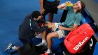 Greece's Stefanos Tsitsipas receives treatment from a trainer during his fourth round match against Switzerland's Roger Federer at the Australian Open tennis championships in Melbourne, Australia, Sunday, Jan. 20, 2019. (AP Photo/Kin Cheung)