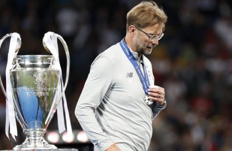 Liverpool coach Jurgen Klopp holds his second place medal as he walks past the trophy after the Champions League Final soccer match between Real Madrid and Liverpool at the Olimpiyskiy Stadium in Kiev, Ukraine, Saturday, May 26, 2018. (AP Photo/Pavel Golovkin)