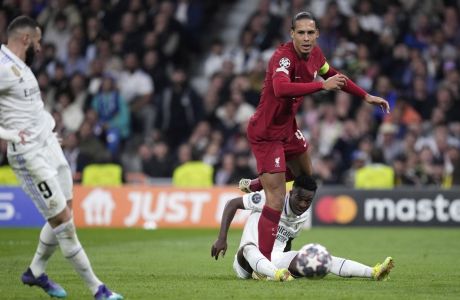 Liverpool's Virgil van Dijk, right left, and Real Madrid's Vinicius Junior, right down, watch as Real Madrid's Karim Benzema scores his sides first goal during the Champions League, round of 16, second leg soccer match between Real Madrid and Liverpool at the Santiago Bernabeu stadium in Madrid, Spain, Wednesday, March 15, 2023. (AP Photo/Bernat Armangue)