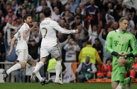 Real Madrid's Cristiano Ronaldo from Portugal, center, celebrates after scoring with teammate Xabi Alonso, left, as Bayern Munich's goalkeeper Manuel Neuer reacts during a semifinal, second leg Champions League soccer match at the Santiago Bernabeu stadium in Madrid Wednesday April 25, 2012. (AP Photo / Franz Mann)