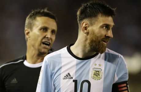 In this photo taken Thursday March 23, 2017 assistant referee Emerson Augusto de Carvalho, left, talks to Argentina's Lionel Messi, right, during a World Cup qualifying match against Chile in Buenos Aires, Argentina. Messi has been banned from Argentina's next four World Cup qualifiers, starting with Tuesday's game in Bolivia, for "having directed insulting words at an assistant referee" during a home qualifier against Chile on Thursday, FIFA said hours before kickoff in La Paz.(AP Photo/Victor R. Caivano)