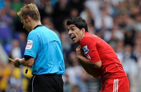 Liverpool's Luis Suarez, right, reacts after referee Mike Jones, left, shows him a yellow card during their English Premier League soccer match against Tottenham Hotspur at White Hart Lane stadium, London, Sunday, Sept. 18, 2011. (AP Photo/Tom Hevezi)
