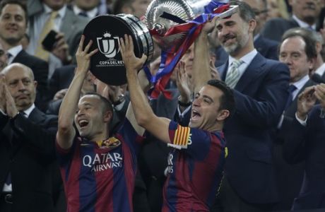 Barcelona's Andres Iniesta, left and Xavi Hernandez lift the cup in front to Spain's King Felipe V1 after winning the final of the Copa del Rey soccer match 3-1against Athletic Bilbao at the Camp Nou stadium in Barcelona, Spain, Saturday, May 30, 2015. (AP Photo/Emilio Morenatti)