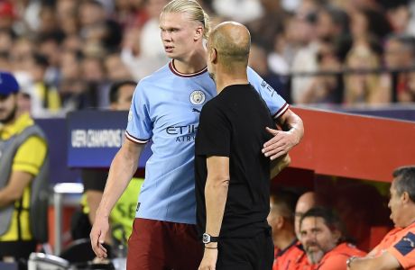 Manchester City's Erling Haaland stands on the touchline with Manchester City's head coach Pep Guardiola during the group G Champions League soccer match between Sevilla and Manchester City in Seville, Spain, Tuesday, Sept. 6, 2022. (AP Photo/Jose Breton)