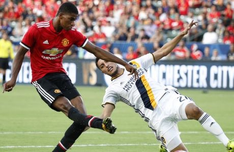 Manchester United's Marcus Rashford, left, shoots to score his second goal of the game as he is defended by Los Angeles Galaxy's Hugo Arellano during the first half of a friendly soccer match Saturday, July 15, 2017, in Carson, Calif. (AP Photo/Jae C. Hong)