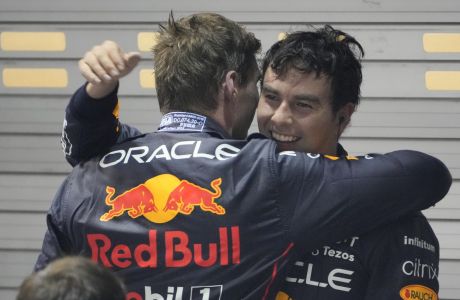Red Bull driver Sergio Perez, right, of Mexico is congratulated by teammate Max Verstappen of the Netherlands after winning the Singapore Formula One Grand Prix, at the Marina Bay City Circuit in Singapore, Sunday, Oct.2, 2022. (AP Photo/Vincent Thian )