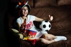 An image of a girl on a sofa watching football on TV