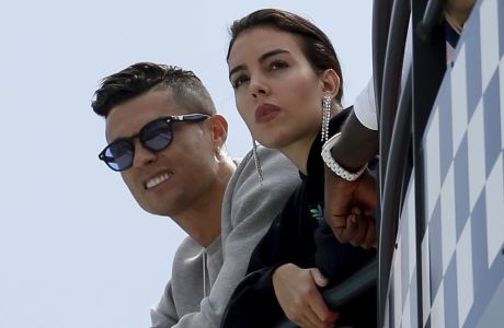 FILE - In this May 23, 2019, file photo, Cristiano Ronaldo, left, is flanked by his partner Georgina Rodriguez as they watch the second practice session for a Formula One race at the Monaco racetrack, in Monaco. Cristiano Ronaldo could be in trouble after apparently breaking coronavirus restrictions on a two-day trip to the mountains. The Juventus star and his partner Georgina Rodriguez spent Tuesday and Wednesday in Courmayeur in the Valle DAosta region in northwest Italy. (AP Photo/Luca Bruno, File)