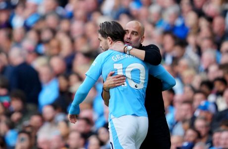 Manchester City's head coach Pep Guardiola hugs Jack Grealish before he replaces teammate Phil Foden during the English Premier League soccer match between Manchester City and Nottingham Forest at Etihad stadium in Manchester, England, Saturday, Sept. 23, 2023. (AP Photo/Jon Super)