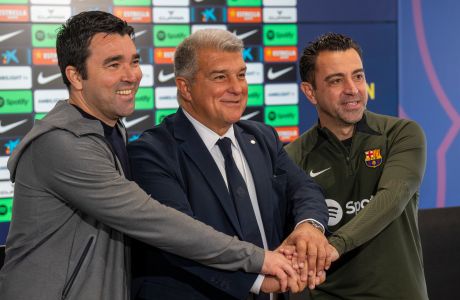 Barcelona's head coach Xavi Hernandez, right, Barcelona's president Joan Laporta, center, and the sports director of the Club, Deco, join hands during a press conference in Barcelona, Spain, Thursday, April 25, 2024. Coach Xavi Hernández will stay with Barcelona for another year after all. He has agreed with the club to finish his contract to 2025 after having decided to quit at the end of the season. (AP Photo/Emilio Morenatti)
