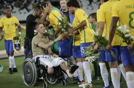 In this Jan 25, 2017 photo, former Chapecoense goalkeeper Follmann, in wheelchair, and Alan Ruschel, behind him, greet Brazil's soccer players prior to a friendly match with Colombia in Rio de Janeiro, Brazil. The match is a tribute to Chapecoense soccer players who died in a plane crash in Colombia last November. Follmann and Ruschel survived the crash. (AP Photo/Silvia Izquierdo)