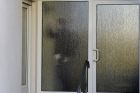 A customs officer walks behind a glass door of a house with a doctor's office during a doping raid in Erfurt, Germany, Wednesday, Feb. 27, 2019. Several people were arrested in doping raids in Austria and Germany during the Nordic skiing world championships. (AP Photo/Jens Meyer)