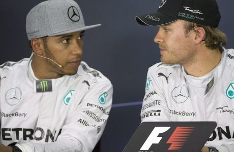 Mercedes driver Nico Rosberg from Germany, right, and teammate Lewis Hamilton, left, who placed second, stare at each other during the post qualifying session news conference at the F1 Canadian Grand Prix auto race, Saturday, June 7, 2014, in Montreal. (AP Photo/The Canadian Press, Graham Hughes)