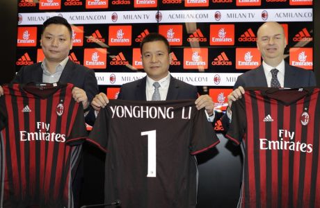 From left, David Han Li, Yonghong Li, and Marco Fassone, pose with AC Milan jerseys during a press conference to illustrate takeover of AC Milan soccer club by a Chinese consortium, in Milan, Italy, Friday, April 14, 2017. A new era began at AC Milan on Thursday after the sale of Italy's most successful club to a Chinese-led consortium ended Silvio Berlusconi's 31 years in charge. (AP Photo/Antonio Calanni)