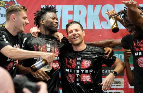 Leverkusen's head coach Xabi Alonso celebrates in a wet shirt, full of beer, at a press conference with his player after taking the Bundesliga title with a 5-0 win against Werder Bremen in Leverkusen, Germany, Sunday, April 14, 2024. (AP Photo/Martin Meissner)