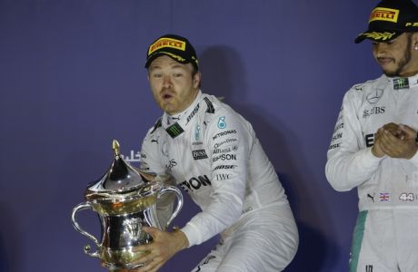 Mercedes driver Nico Rosberg of Germany, left, celebrates on the podium after he won the Bahrain Formula One Grand Prix, at the Formula One Bahrain International Circuit, in Sakhir, Bahrain, Sunday, April 3, 2016. At right is third place is fellow Mercedes driver Lewis Hamilton of Britain. (AP Photo/Luca Bruno)