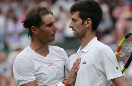 Novak Djokovic of Serbia, right, meets Rafael Nadal of Spain at the net after defeating him in the men's singles semifinal match at the Wimbledon Tennis Championships, in London, Saturday July 14, 2018. (Andrew Couldridge, Pool via AP)