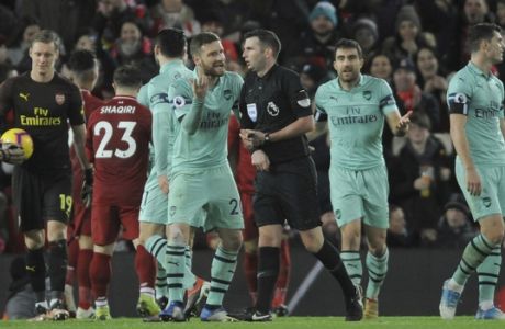 Referee Michael Oliver, centre, is spoken to by Arsenal's Shkodran Mustafi, and Arsenal's Sokratis Papastathopoulos after Oliver awarded a penalty to Liverpool during the English Premier League soccer match between Liverpool and Arsenal at Anfield in Liverpool, England, Saturday, Dec. 29, 2018. (AP Photo/Rui Vieira)