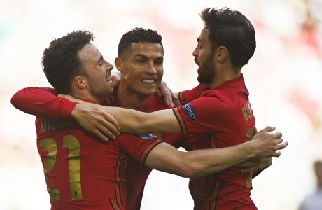 Portugal's Cristiano Ronaldo, center, celebrates with Diogo Jota and Bernardo Silva, right, after scoring the opening goal during the Euro 2020 soccer championship group F match between Portugal and Germany at the Football Arena stadium in Munich, Germany, Saturday, June 19, 2021. (Philipp Guelland/Pool via AP)