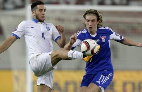 Greece's Kostas Manolas, left, in close action with Faroe Islands' player Joan Edmundsson during the Group F Euro 2016 qualifying soccer match between Greece and Faroe Islands, at the Georgios Karaiskakis stadium, in the port of Piraeus, near Athens on Friday, Nov. 14, 2014. (AP Photo/Thanassis Stavrakis)