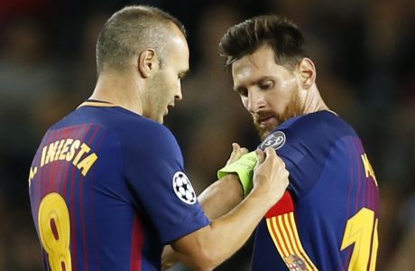Barcelona's Andres Iniesta hands over the captain's armband to Lionel Messi during a Champions League group D soccer match between FC Barcelona and Juventus at the Camp Nou stadium in Barcelona, Spain, Tuesday, Sept. 12, 2017. (AP Photo/Francisco Seco)