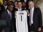 President Barack Obama, center, smiles with a jersey given to him by guard Kemba Walker, left, and coach Jim Calhoun as Obama greeted the Connecticut men's basketball team in the East Room of the White House, Monday, May 16, 2011, in Washington.  (AP Photo/Carolyn Kaster)