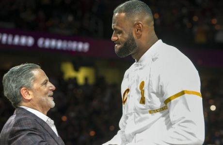 Cleveland Cavaliers' LeBron James accepts his NBA championship ring from Cavaliers owner Dan Gilbert before a basketball game against the New York Knicks in Cleveland, Tuesday, Oct. 25, 2016. (AP Photo/Phil Long)