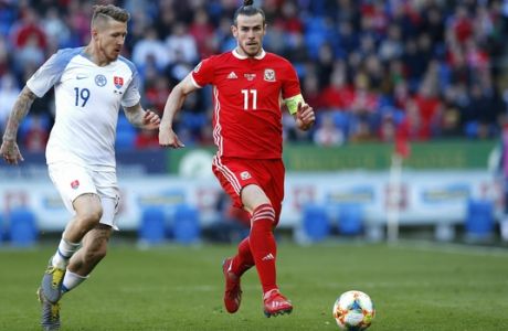 Slovakia's Juraj Kucka, left, and Wales' Gareth Bale battle for the ball during the Euro 2020 qualifying, Group E soccer match at the Cardiff City Stadium, Wales, Sunday March 24, 2019. (Darren Staples/PA via AP)