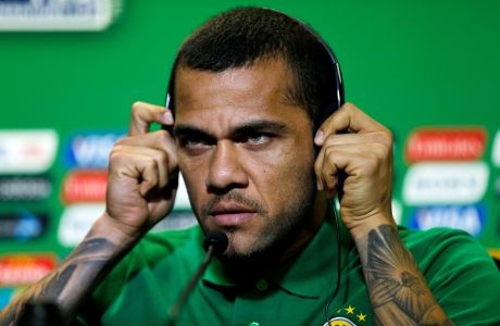 Brazil's Dani Alves adjusts the headphones during a news conference in Salvador, Brazil, Friday, June 21, 2013. Brazil will face Italy  at the soccer Confederations Cup on Saturday. (AP Photo/Fernando Llano)