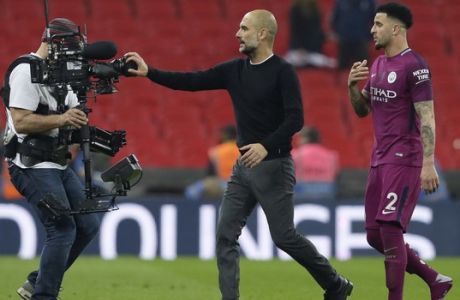Manchester City coach Pep Guardiola covers a video camera with his hand as he leaves the field with Manchester City's Kyle Walker, right, at the end of the English Premier League soccer match between Tottenham Hotspur and Manchester City at Wembley stadium in London, England, Saturday, April 14, 2018. Manchester City won 3-1. (AP Photo/Tim Ireland)