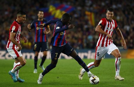 Barcelona's Ousmane Dembele, center, controls the ball past Athletic Bilbao's Mikel Vesga, right, during a Spanish La Liga soccer match between Barcelona and Athletic Club at the Camp Nou stadium in Barcelona, Spain, Sunday, Oct. 23, 2022. (AP Photo/Joan Monfort)