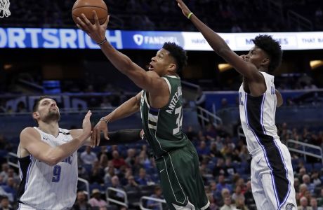 Milwaukee Bucks' Giannis Antetokounmpo, center, gets off a shot between Orlando Magic's Nikola Vucevic (9) and Jonathan Isaac, right, during the first half of an NBA basketball game, Wednesday, March 14, 2018, in Orlando, Fla. (AP Photo/John Raoux)