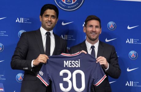 Lionel Messi, right, poses with his jersey with PSG president Nasser Al-Al-Khelaifi during a press conference Wednesday, Aug. 11, 2021 at the Parc des Princes stadium in Paris. Lionel Messi said he's been enjoying his time in Paris "since the first minute" after he signed his Paris Saint-Germain contract on Tuesday night. The 34-year-old Argentina star signed a two-year deal with the option for a third season after leaving Barcelona. (AP Photo/Francois Mori)