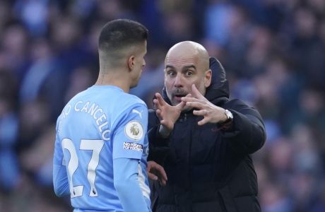 Manchester City's head coach Pep Guardiola, right, gives instructions to his player Joao Cancelo during the English Premier League soccer match between Manchester City and Manchester United, at the Etihad stadium in Manchester, England, Sunday, March 6, 2022. (AP Photo/Jon Super)