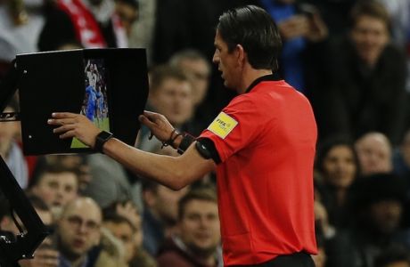 Referee Deniz Aytekin of Germany looks at a VAR replay, which led him to award Italy a panalty, during the friendly soccer match between England and Italy at Wembley stadium London, Tuesday, March, 27, 2018. (AP Photo/Alastair Grant)
