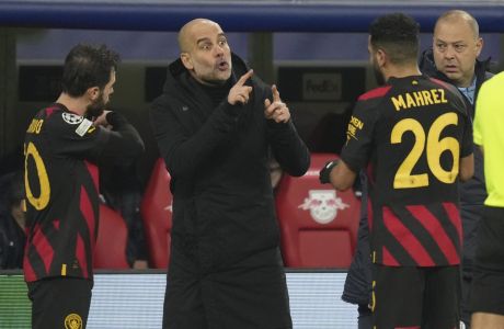 Manchester City's head coach Pep Guardiola speaks to Manchester City's Bernardo Silva, left, and Riyad Mahrez during the Champions League round of 16 first leg soccer match between RB Leipzig and Manchester City in Leipzig, Germany, Wednesday, Feb 22, 2023. (AP Photo/Michael Sohn)