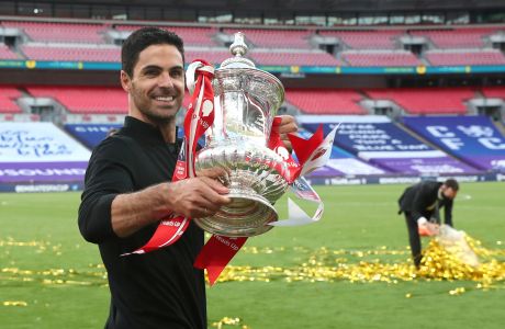 Arsenal's head coach Mikel Arteta walks with the trophy after the FA Cup final soccer match between Arsenal and Chelsea at Wembley stadium in London, England, Saturday, Aug.1, 2020. (Catherine Ivill/Pool via AP)