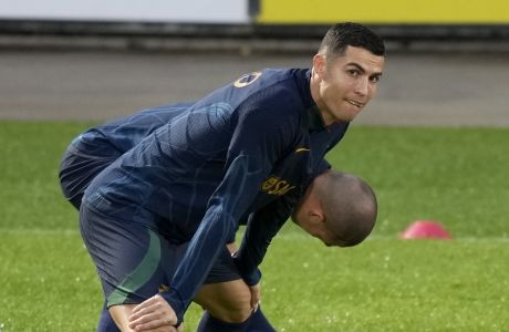 Cristiano Ronaldo stretches with teammate Pepe, in the background, during a Portugal soccer team training session in Oeiras, outside Lisbon, Monday, Nov. 14, 2022. Portugal will play Nigeria Thursday in a friendly match in Lisbon before departing to Qatar on Friday for the World Cup. (AP Photo/Armando Franca)