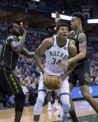 Milwaukee Bucks forward Giannis Antetokounmpo, center, is defended by Atlanta Hawks guard Kent Bazemore, left, and John Collins, right, during the first half of an NBA basketball game Tuesday, Feb. 13, 2018, in Milwaukee. (AP Photo/Darren Hauck)