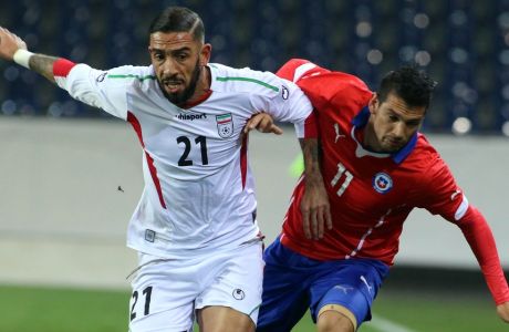 Iran's Ashkan Dejagah, left, challenges Chile's Mark Gonzalez for the ball during the friendly soccer match between Iran and Chile in St. Poelten, Austria, Thursday, March 26, 2015. (AP Photo/Ronald Zak)