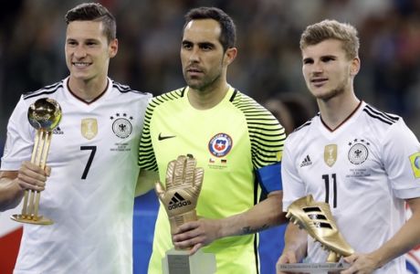 Germany's Julian Draxler, Chile goalkeeper Claudio Bravo and Germany's Timo Werner, from left to right, hold their individual trophies at the end of the Confederations Cup final soccer match between Chile and Germany, at the St.Petersburg Stadium, Russia, Sunday July 2, 2017. Germany won 1-0. (AP Photo/Thanassis Stavrakis)