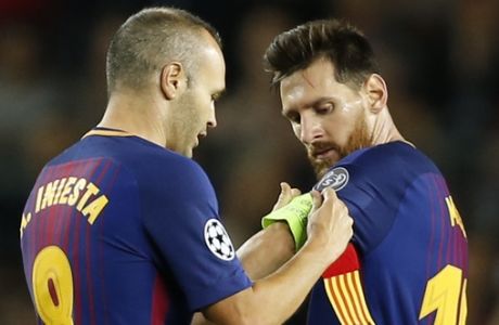 Barcelona's Andres Iniesta hands over the captain's armband to Lionel Messi during a Champions League group D soccer match between FC Barcelona and Juventus at the Camp Nou stadium in Barcelona, Spain, Tuesday, Sept. 12, 2017. (AP Photo/Francisco Seco)