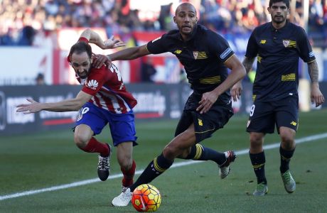 Atletico Madrid's Juan Francisco Torres Juanfran, left, tussles for the ball with Sevilla's Steven NZonzi, center, during a Spanish La Liga soccer match between Atletico Madrid and Sevilla at the Vicente Calderon stadium in Madrid, Sunday, Jan. 24, 2016. The match ended in a 0-0 draw. (AP Photo/Francisco Seco)
