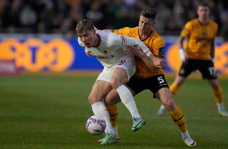 Manchester United's Rasmus Hojlund, left, is challenged by Newport's James Clarke during the FA Cup fourth round soccer match between Newport County and Manchester United at the Rodney Parade stadium in Newport, Wales, Sunday, Jan. 28, 2024. (AP Photo/Alastair Grant)
