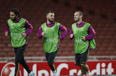 Galatasaray's Wesley Sneijder, right, and Emre Colak, centre, share a joke as they warm up during a training session, Tuesday, Sept. 30, 2014 at the Emirates Stadium in London, ahead of their Champions League Group D soccer match against Arsenal Wednesday. (AP Photo/Lefteris Pitarakis)